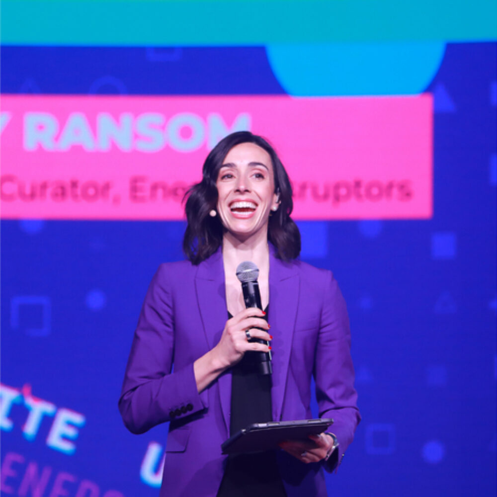 Holly Ransom on stage delivering a powerful message in a purple blazer.